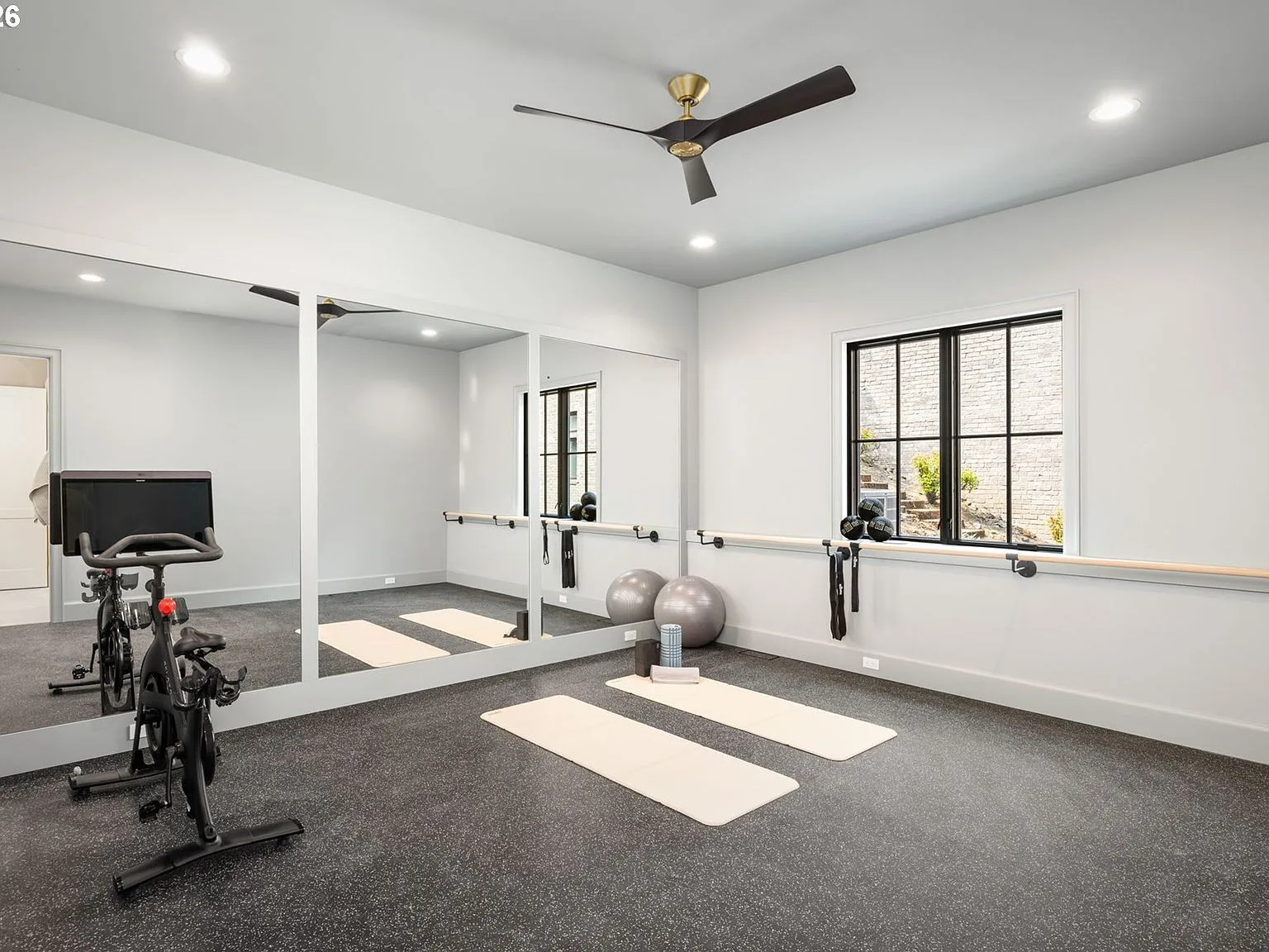 Fitness studio with full-wall mirrors, dark flooring, and black-framed windows