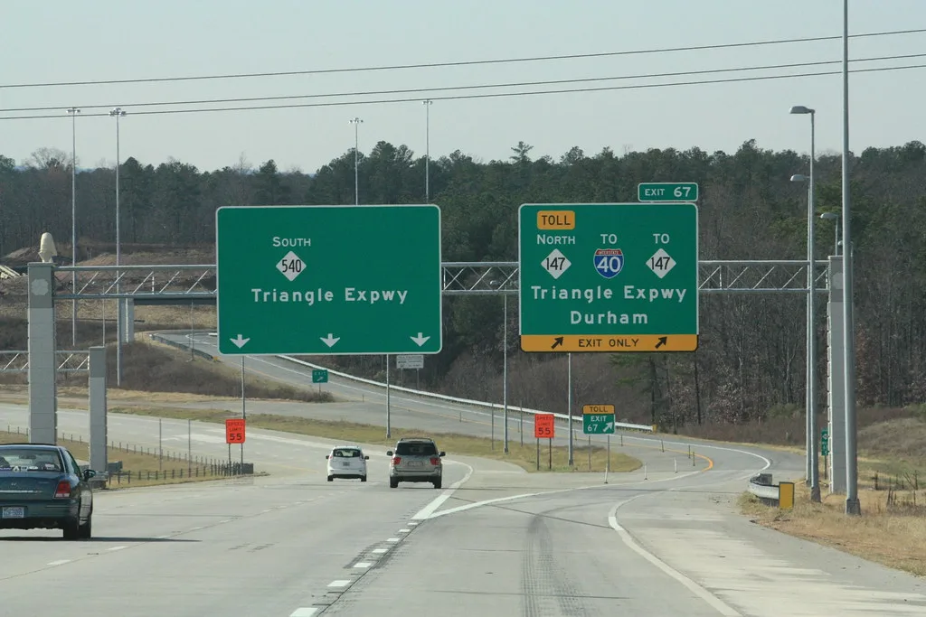 Highway signage at a North Carolina interchange showing directions to Raleigh and surrounding Triangle suburbs