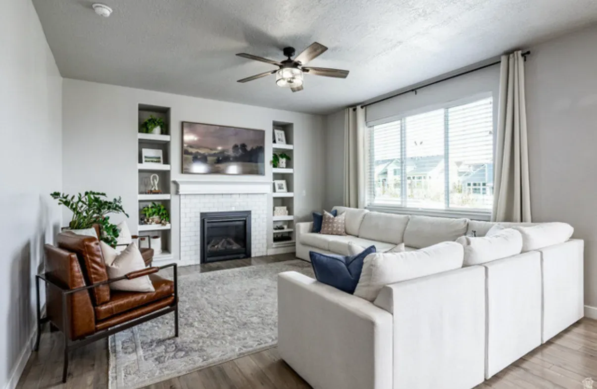 Living room with white brick fireplace, built-in shelving, and natural light from large windows
