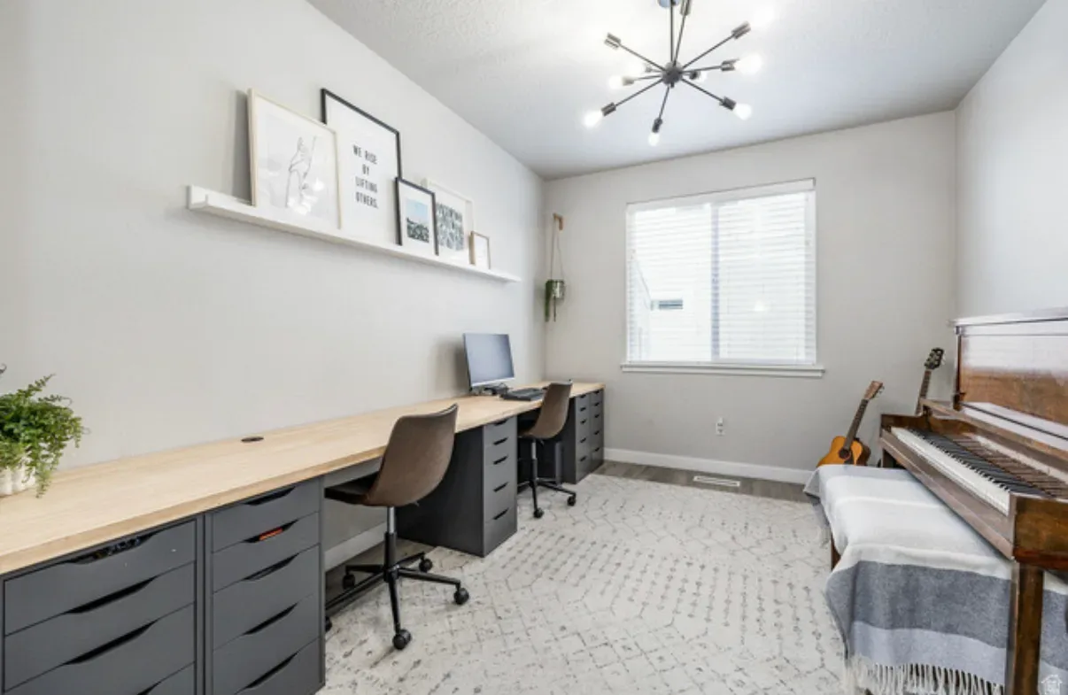 Bedroom configured as a home office with desk, piano, and natural window light