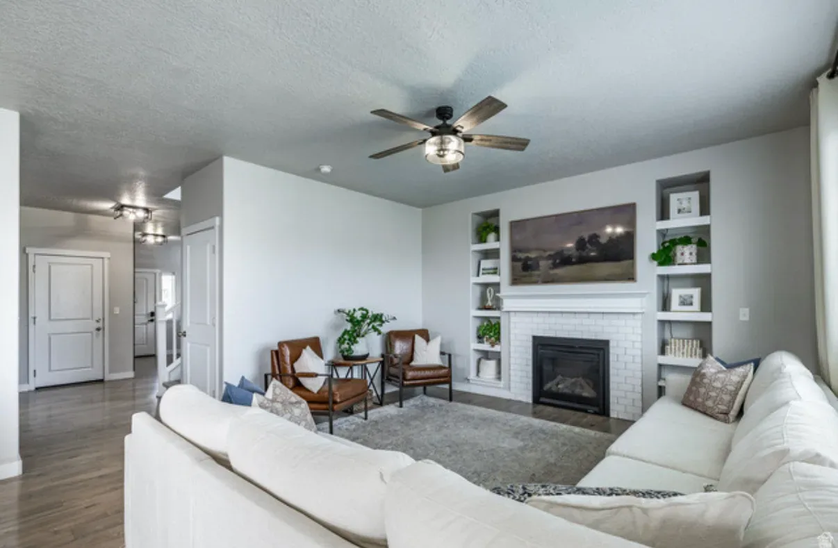 Alternate angle of living room showing fireplace, sectional, and hallway view