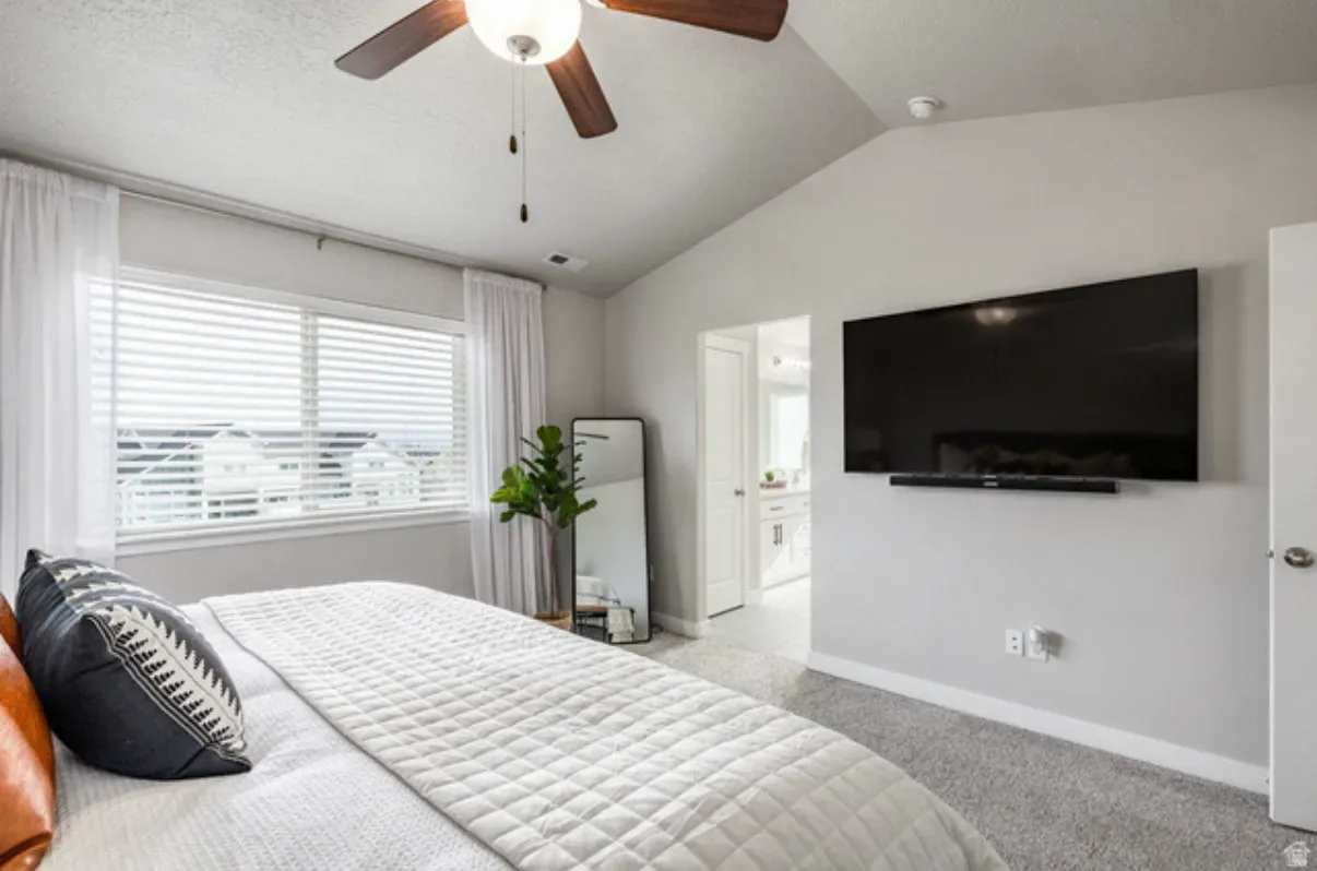 Master bedroom showing vaulted ceiling detail, neutral walls, and carpet flooring
