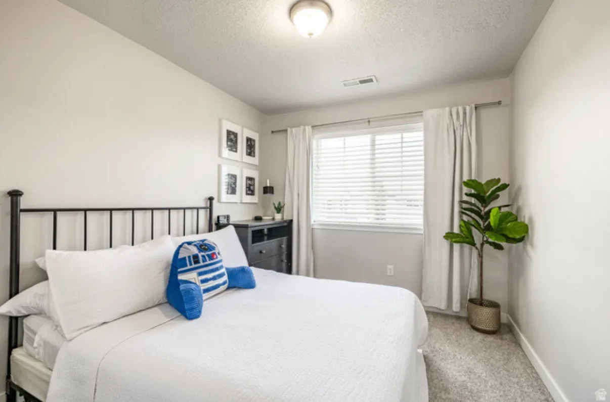 Guest bedroom with black metal bed frame, wall art, and window treatments
