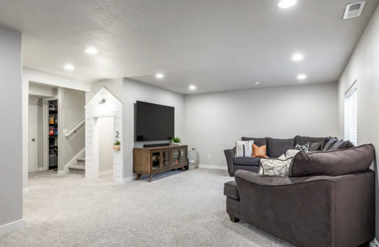 Finished basement living room with recessed lighting and neutral carpet