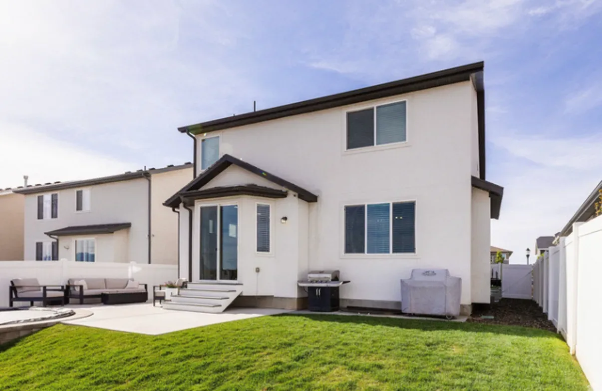 Rear exterior of the two-story home with white stucco siding and dark window frames