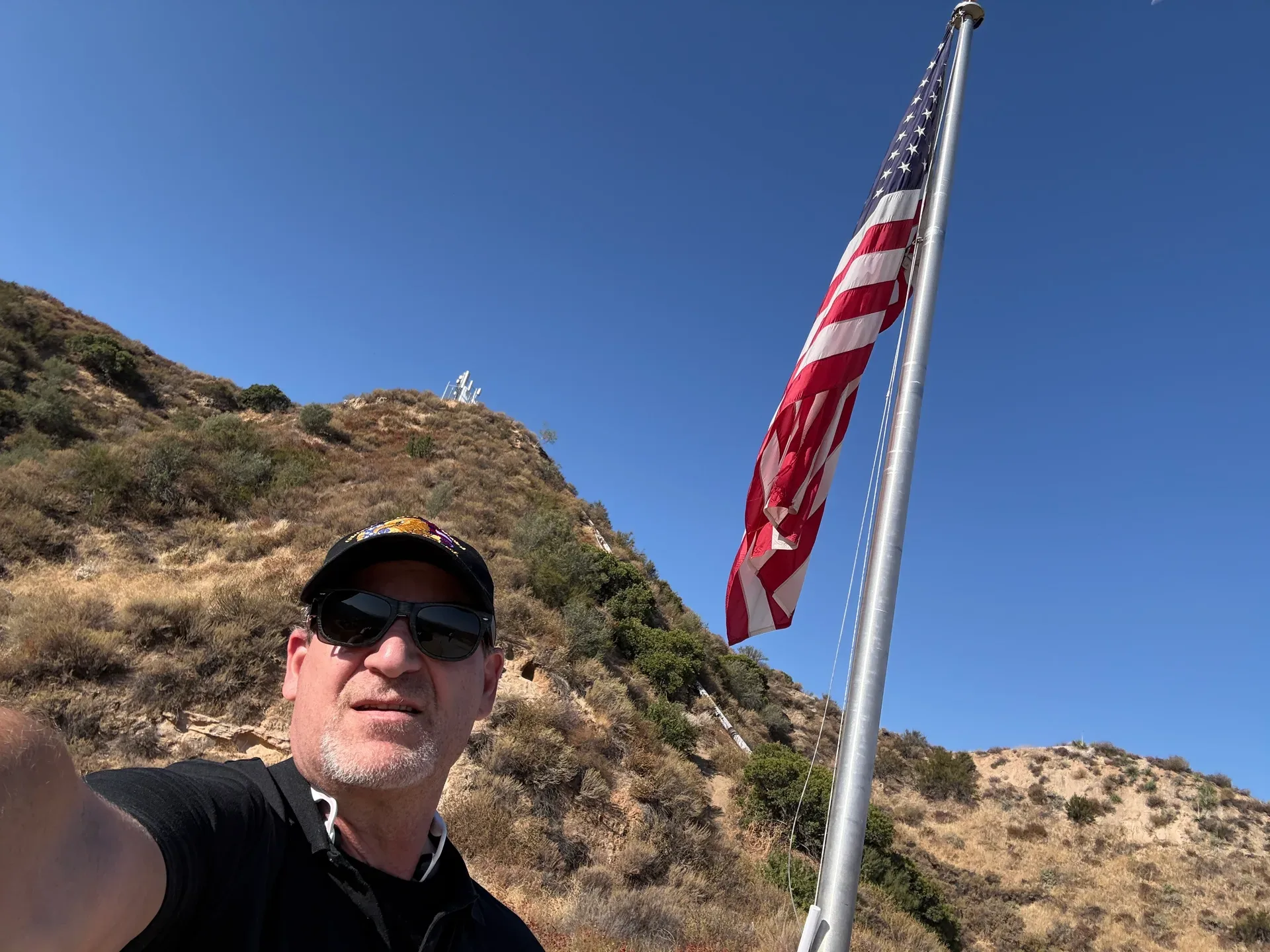 American flag waving at the summit of the SCV Stairs with Santa Clarita Valley hills in the background