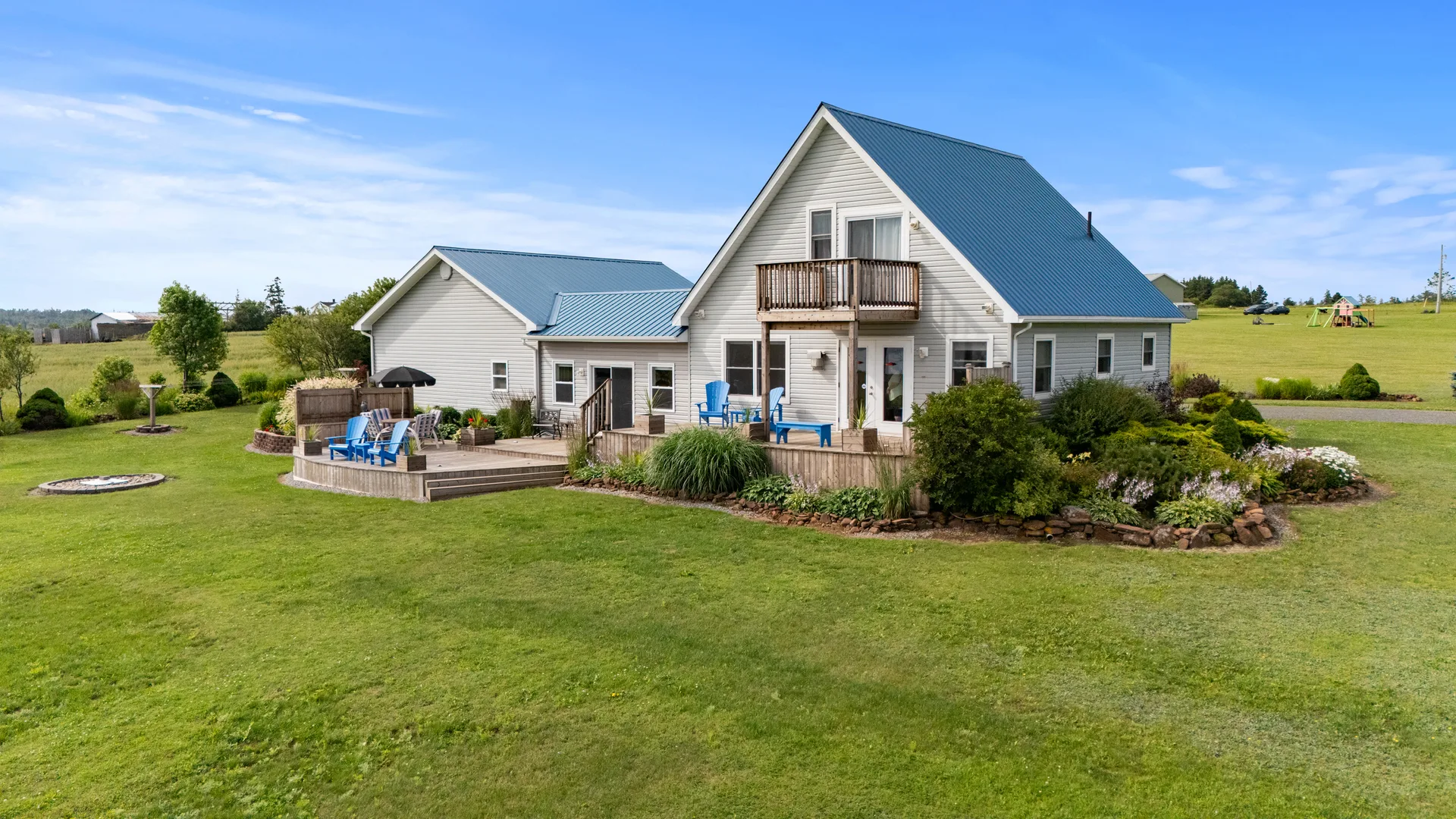 Rear exterior with deck, balcony, and landscaped yard