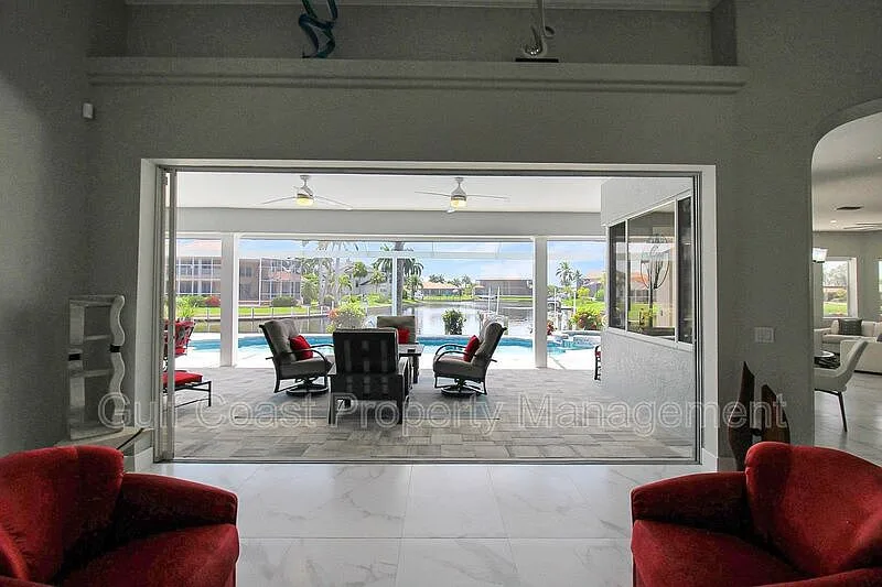 Living room with vaulted ceilings and a view through to the screened pool and canal beyond
