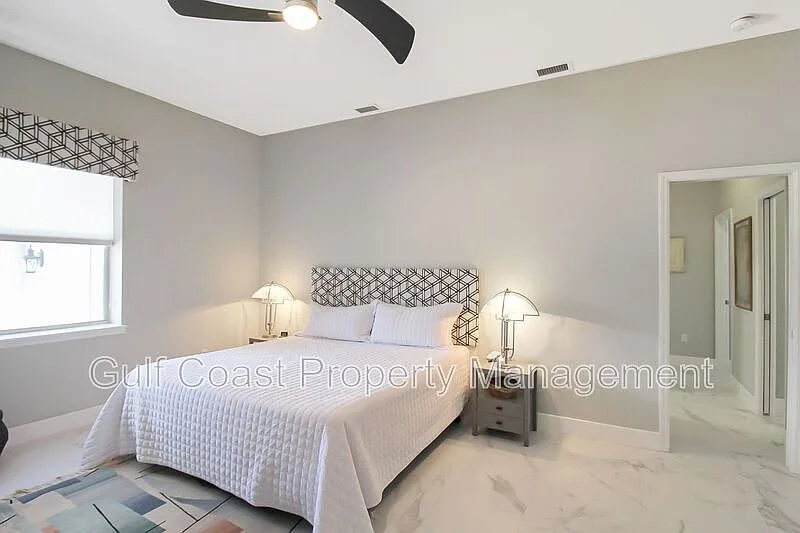 Master bedroom with vaulted ceiling, grey walls, and natural light through large windows
