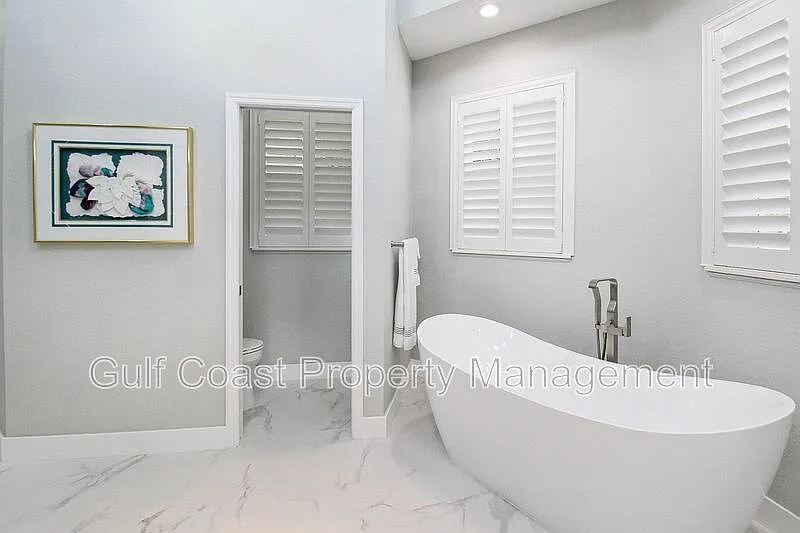 Primary bathroom featuring a freestanding soaking tub and marble-look tile flooring
