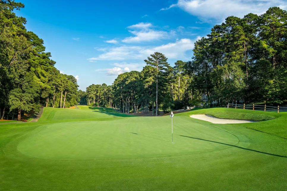 Golf course green with sand bunker ringed by dense pine forest at Treyburn Country Club