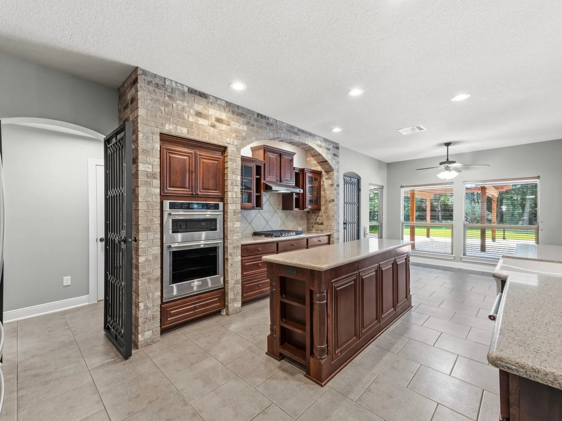 Kitchen with cherry wood cabinetry, brick facade feature wall surrounding the range, and tile flooring