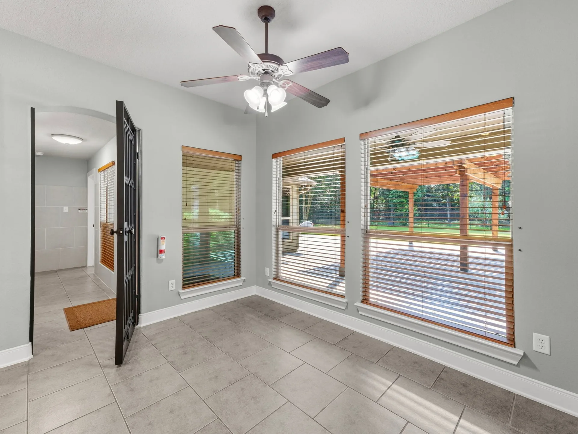 Flex living space with large format tile flooring, neutral walls, and views toward the backyard