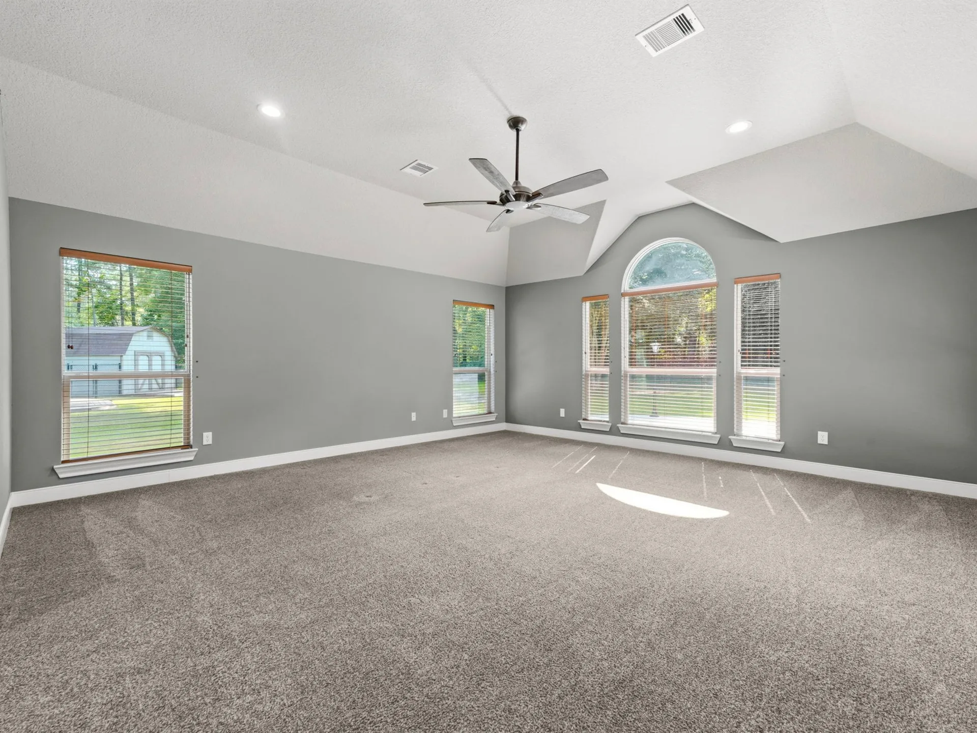 Vacant living room with vaulted ceiling, neutral gray walls, and carpeted flooring
