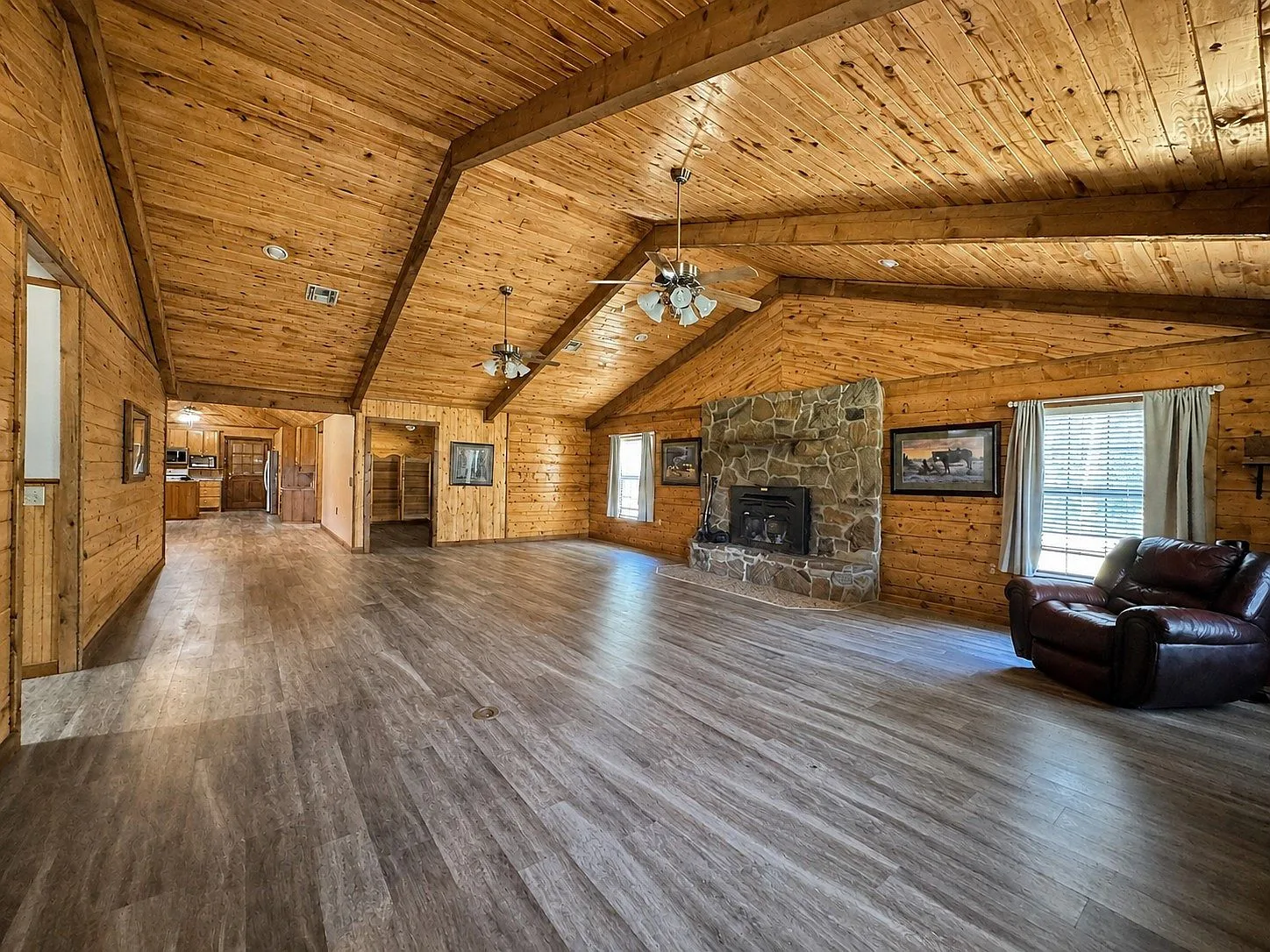 Rustic log cabin living room with stone fireplace and vaulted ceiling