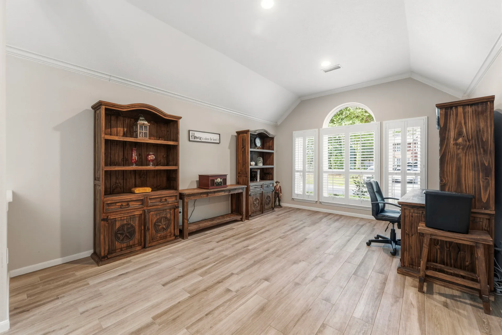Flex room or study with vaulted ceiling, arched window, and plantation shutters