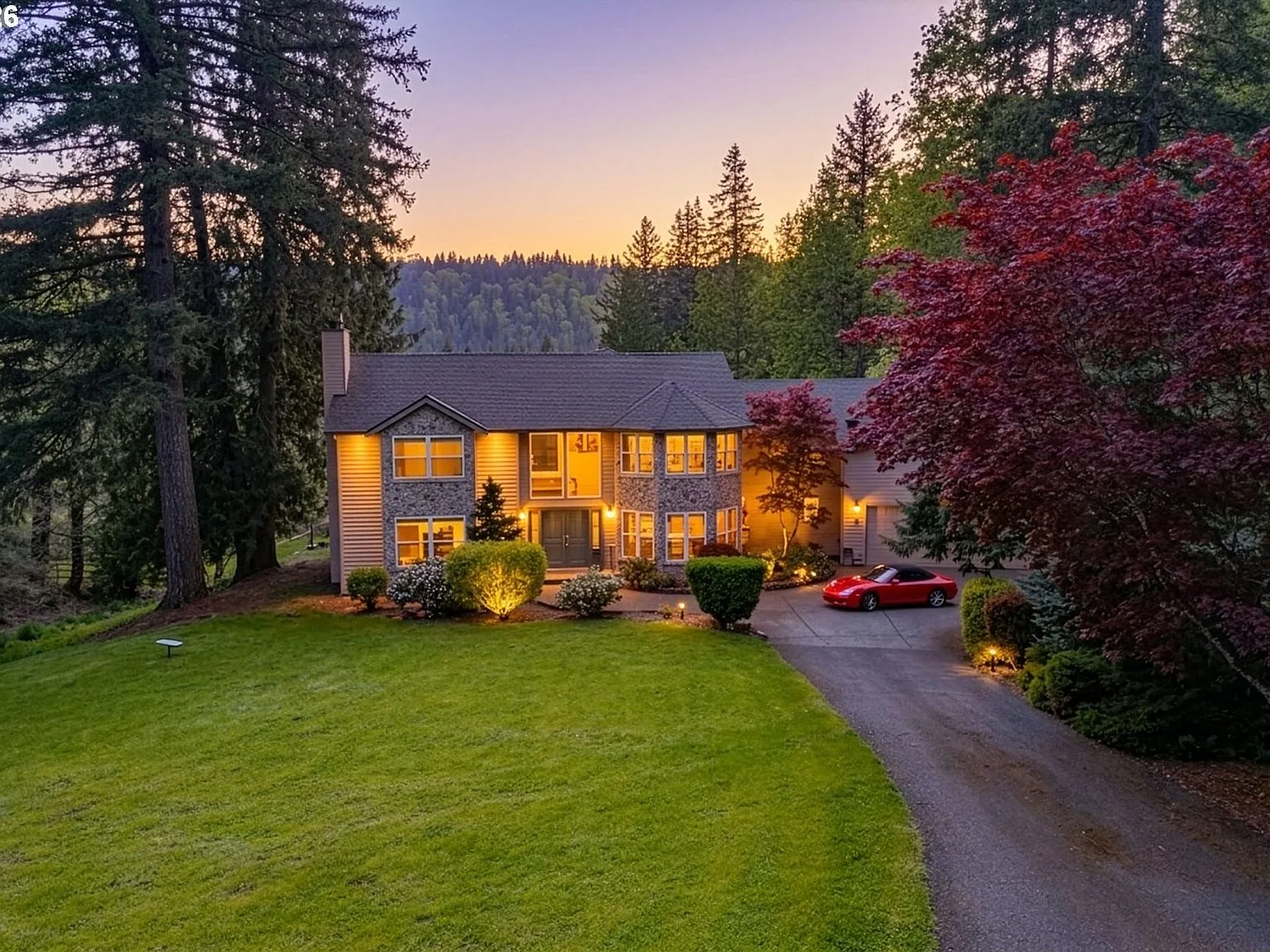 1352 Buhman Rd at twilight, the house lit warm against Pacific Northwest firs