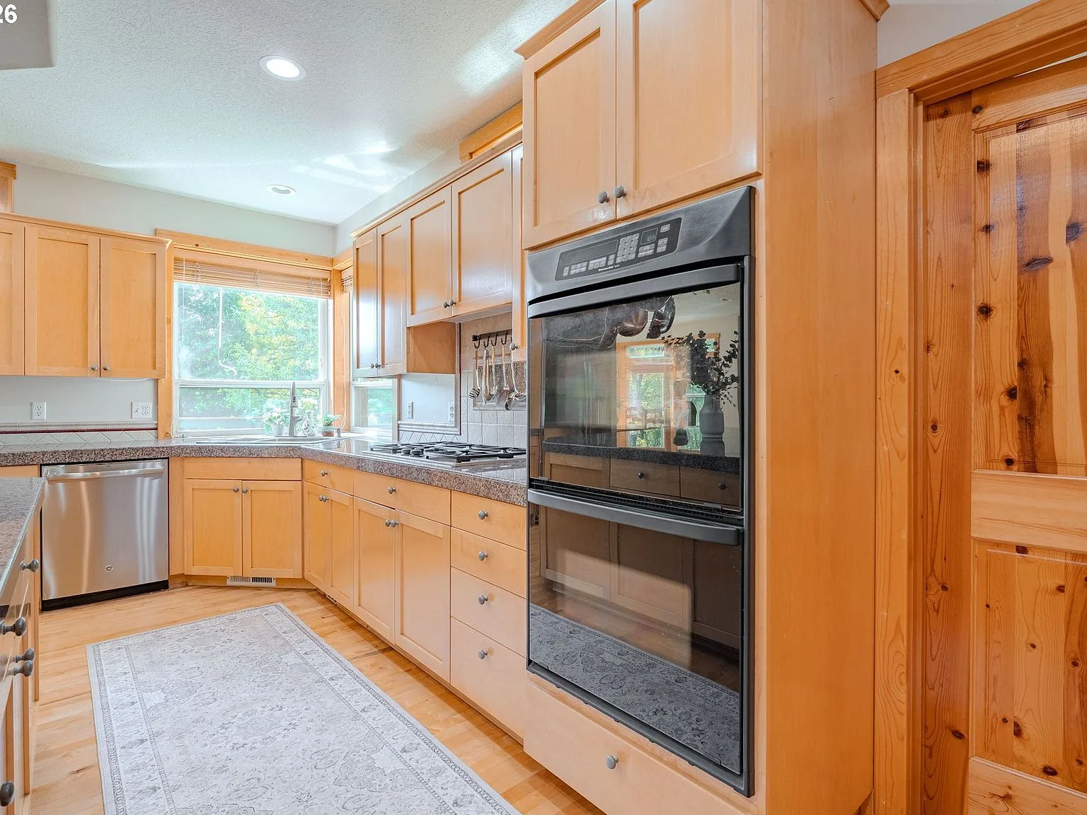 Kitchen cooking wall with natural wood cabinets and granite countertops