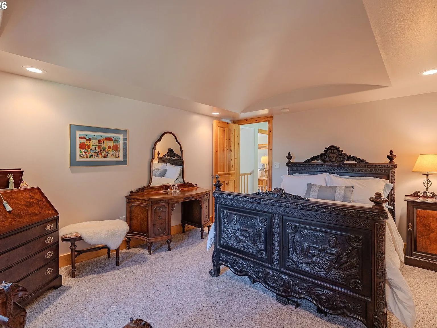 Primary bedroom with vaulted ceiling, carpeted flooring, and antique bed frame