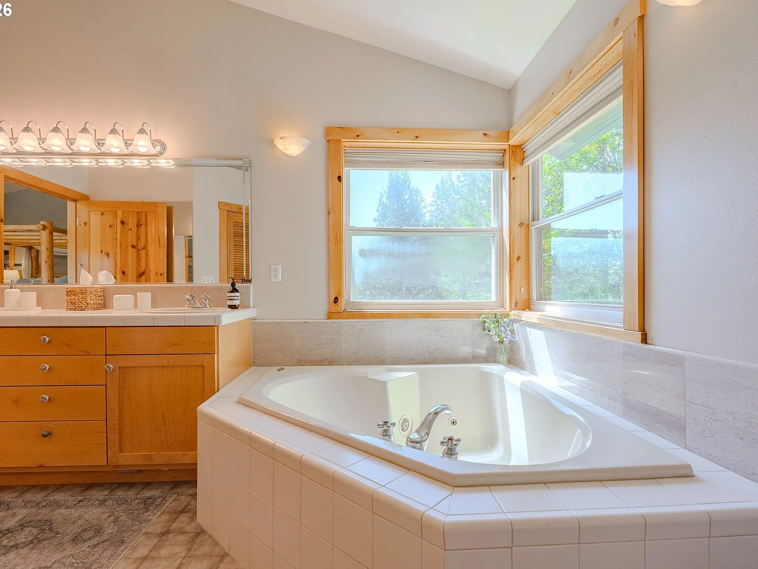 Primary bath corner soaking tub with natural wood trim and windows