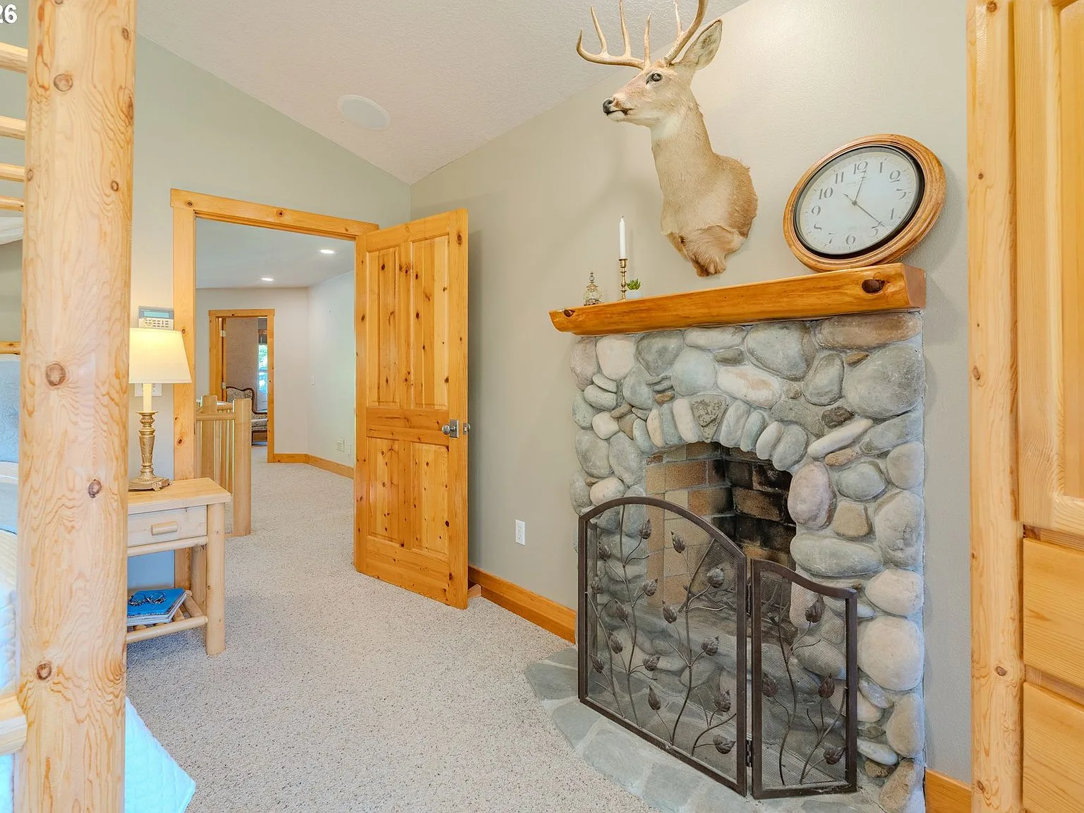 Bedroom with river-rock stone fireplace and wood mantle