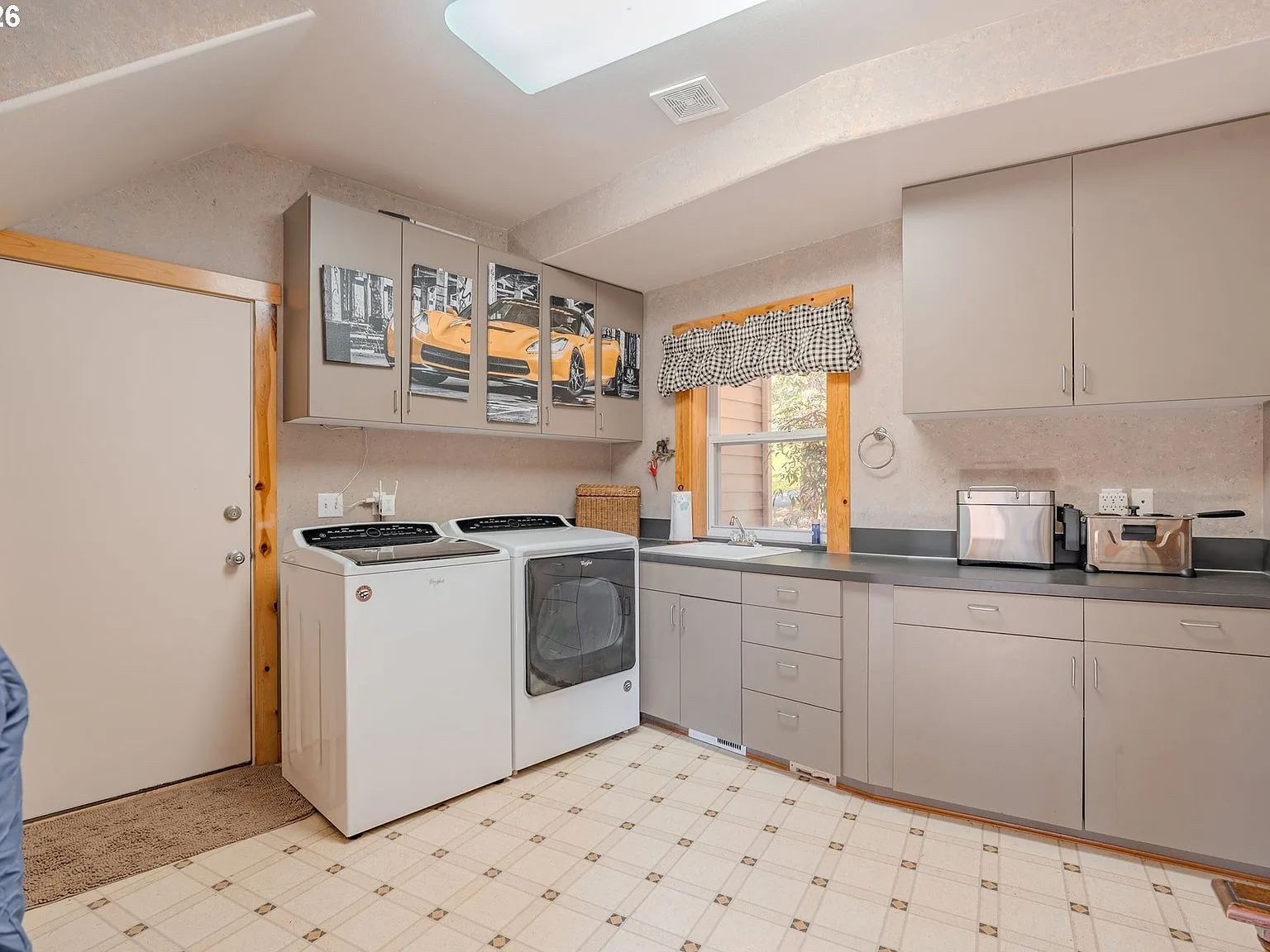 Laundry and mud room with grey cabinets and skylight
