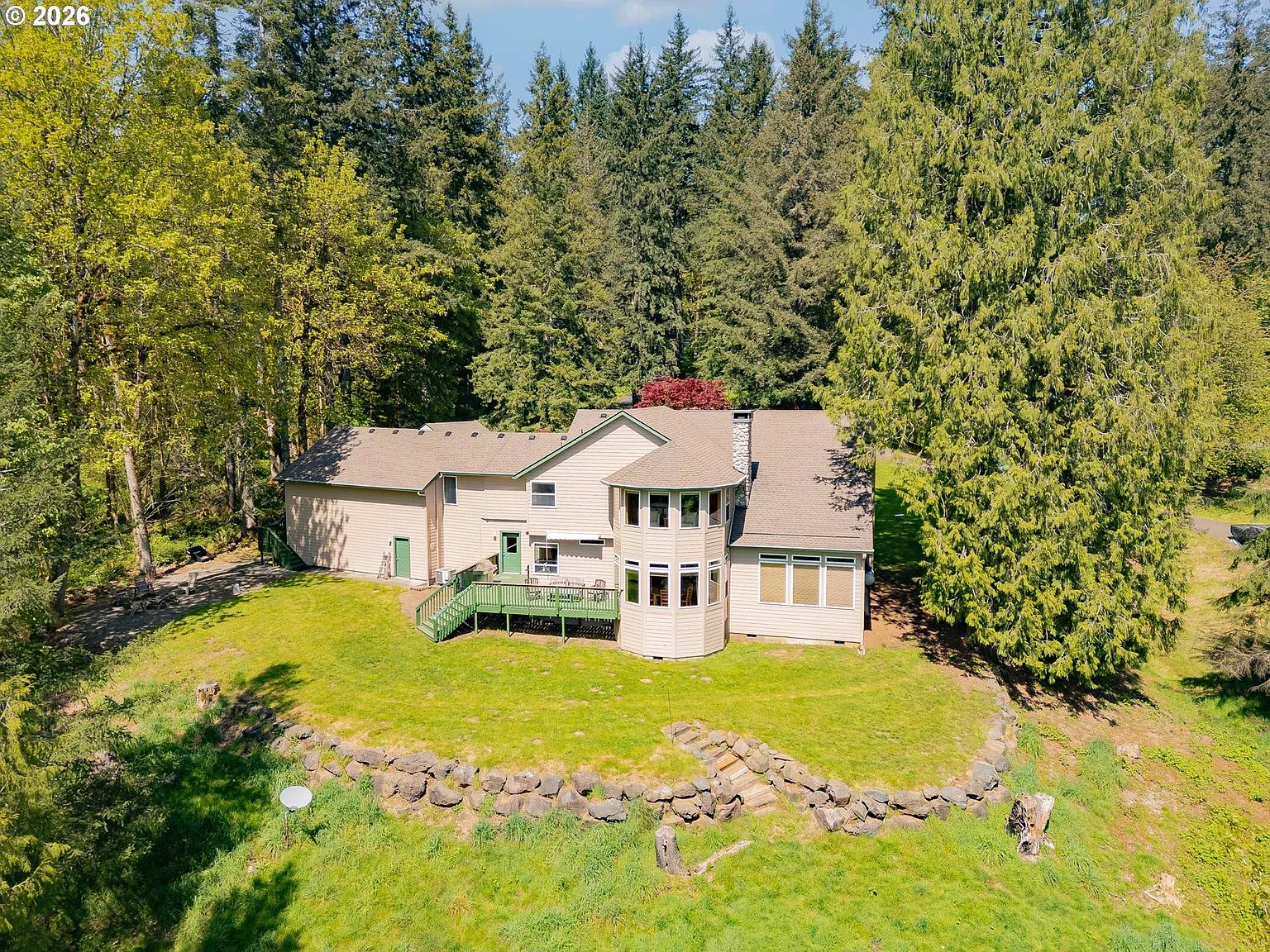 Rear view of the home with deck and stone retaining wall
