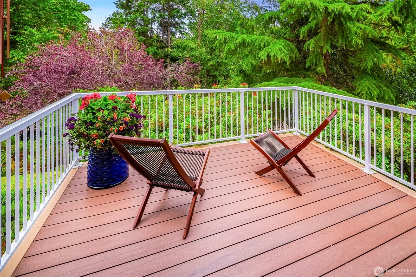 Brand-new deck with white railings overlooking a lush, mature backyard