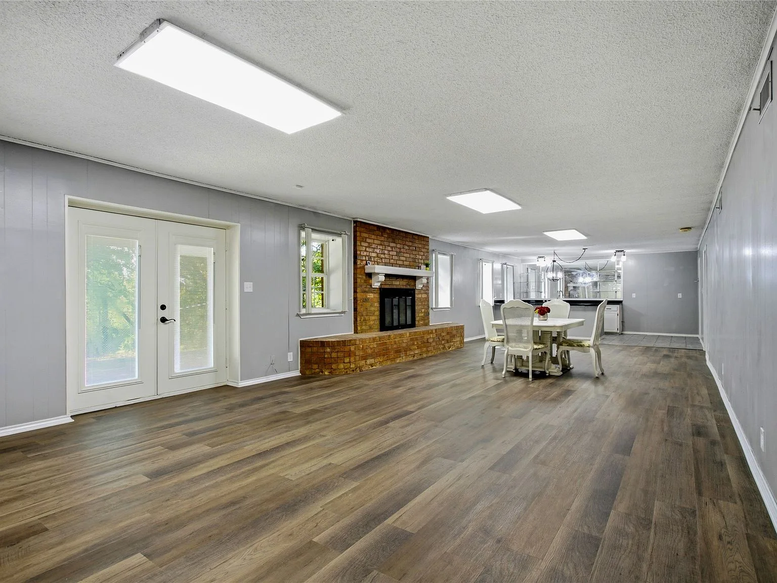 Walk-out basement living and dining area with exposed red brick fireplace