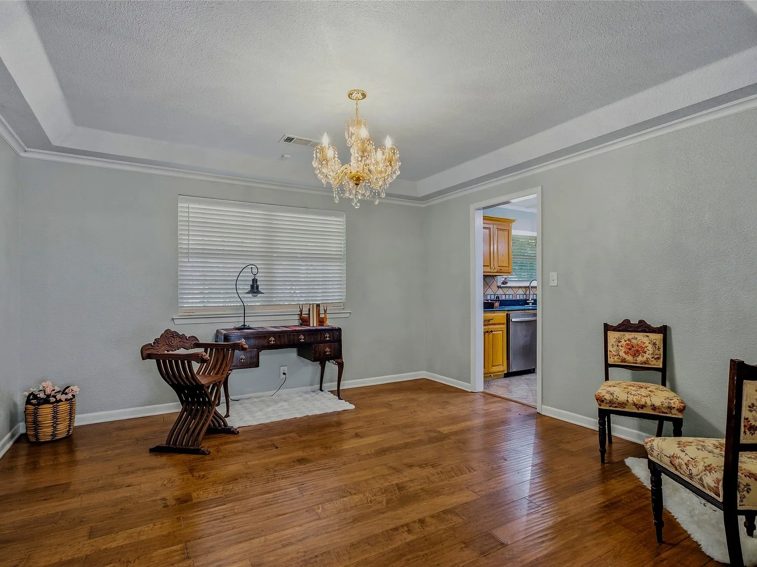 Formal dining room with tray ceiling, crystal chandelier, and hardwood flooring