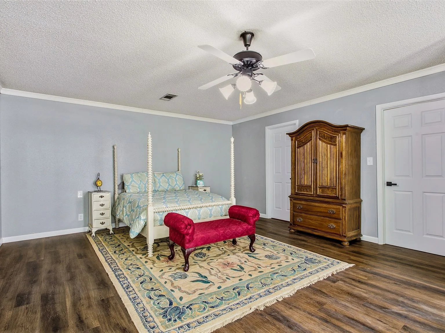 Primary bedroom suite with neutral walls and wood-look flooring