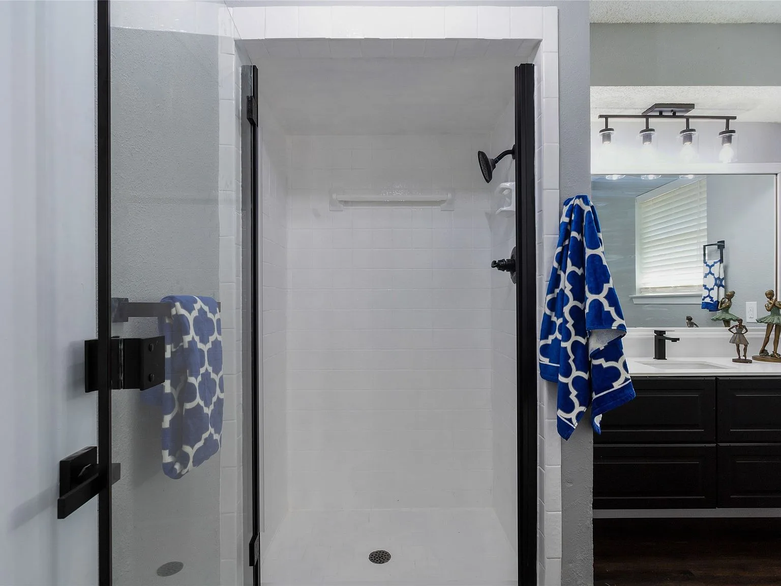 Updated bathroom with white tiled walk-in shower, black hardware, and glass door