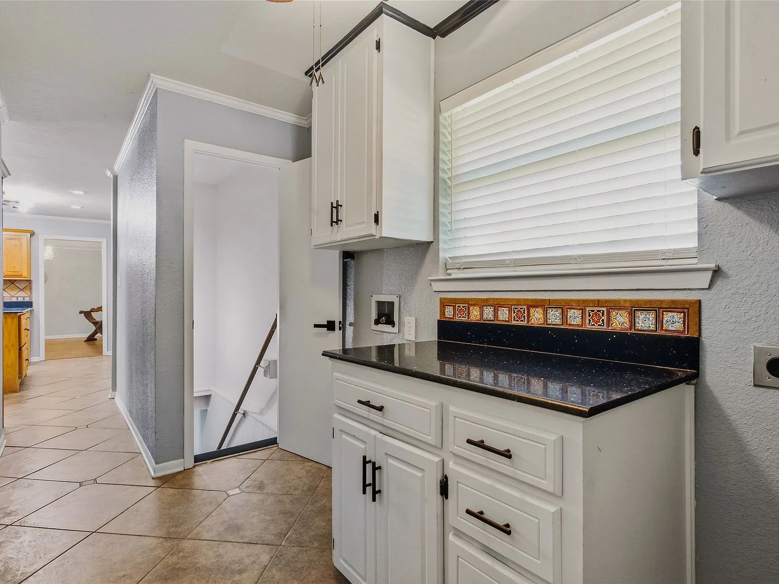 Hallway utility nook with white shaker cabinets and black granite countertops