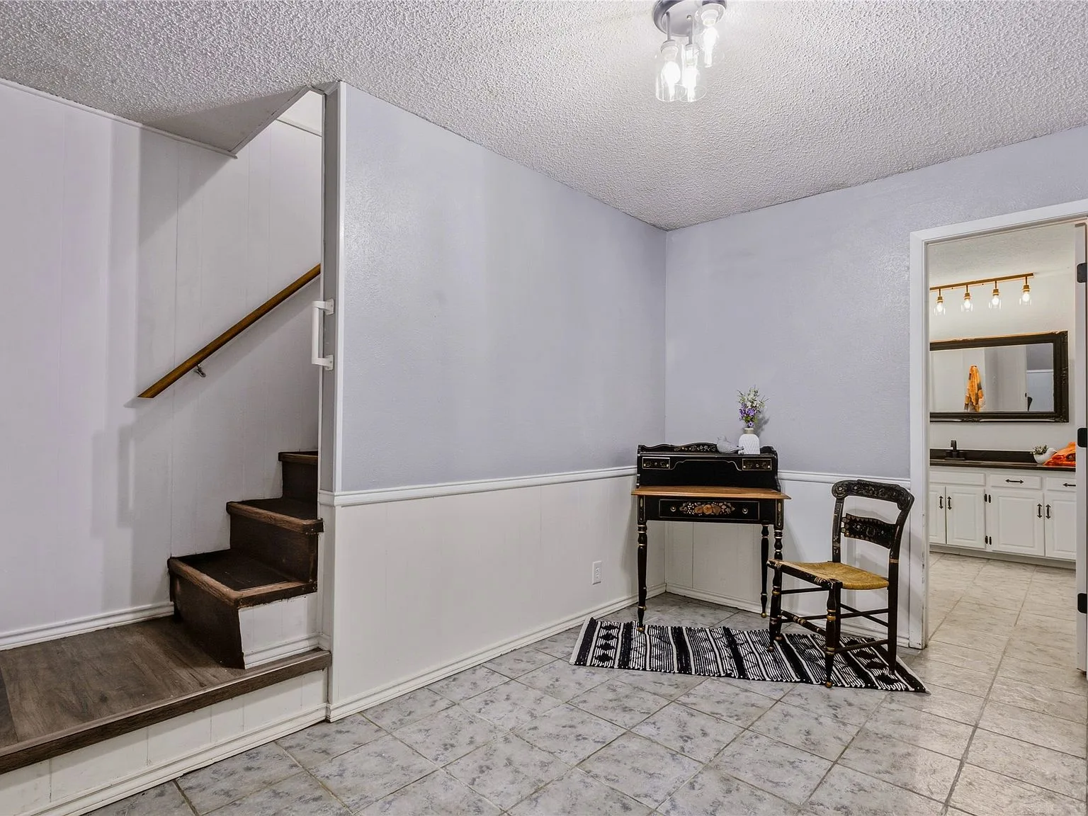 Staircase and landing area with tile floors, white wainscoting, and grey walls