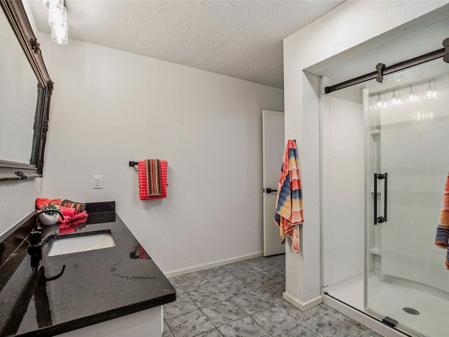 Bathroom with dark granite vanity, under-mount sink, and walk-in shower