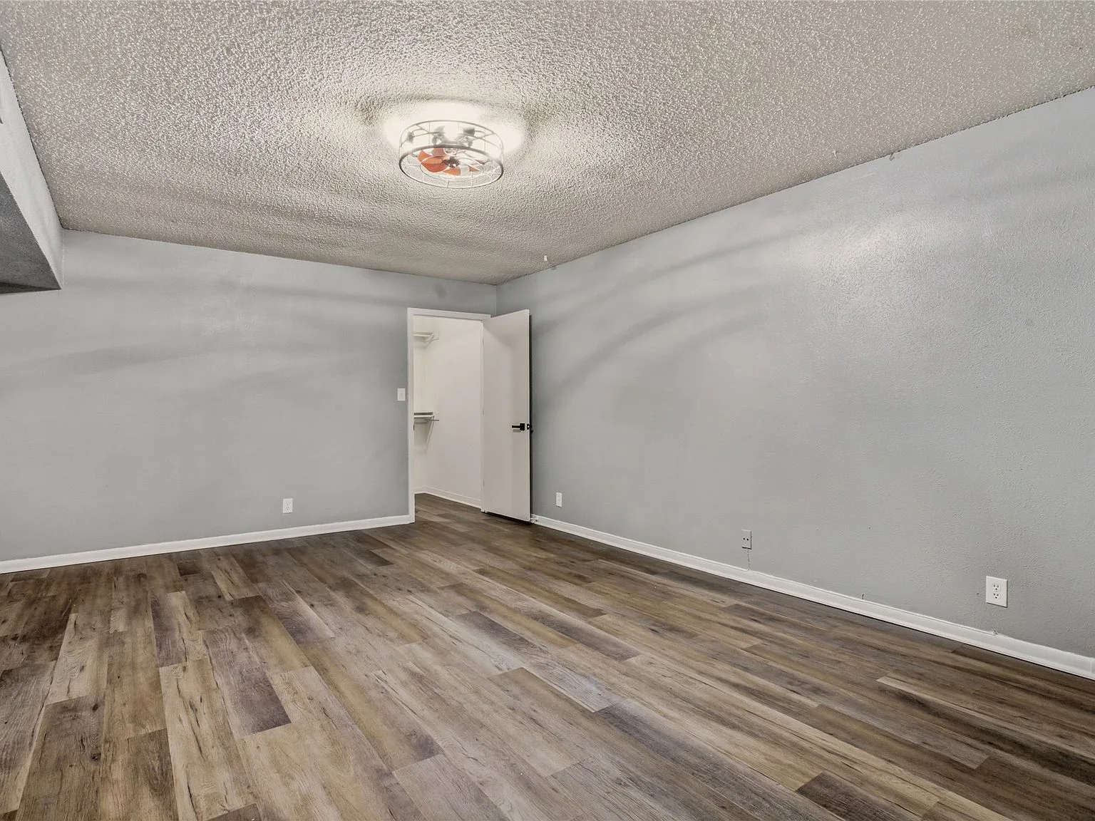 Vacant bedroom with light grey walls and wood-look laminate flooring