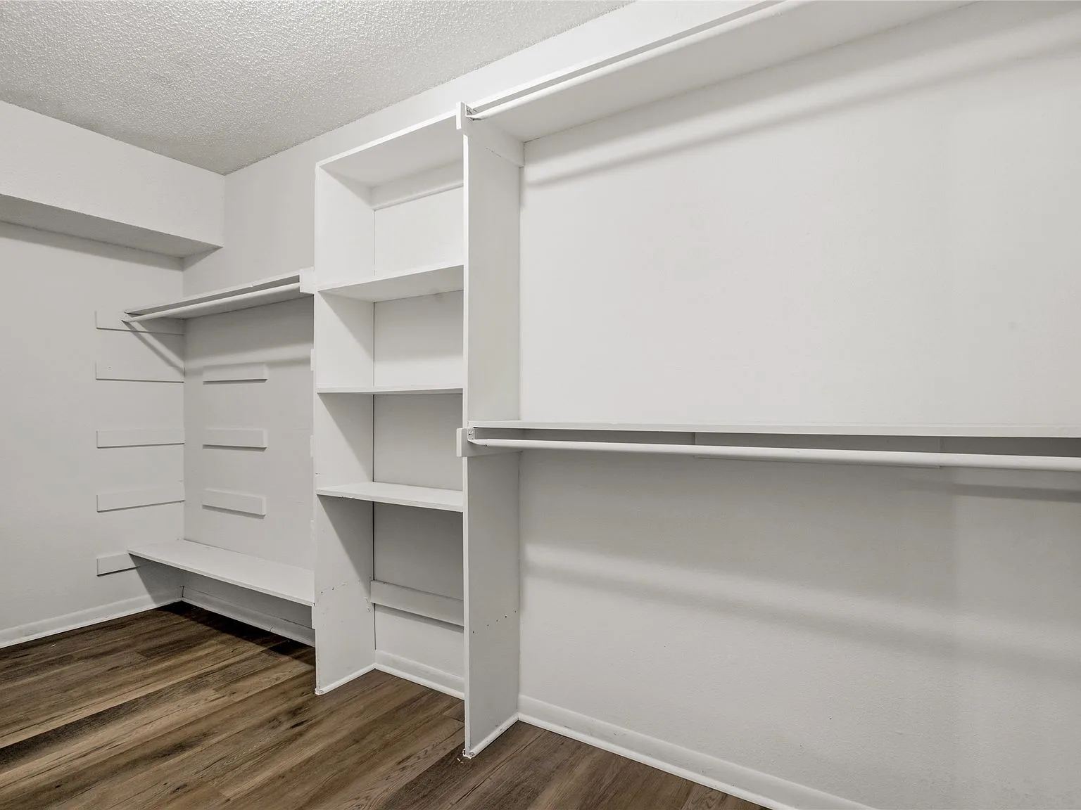 Walk-in closet with white built-in shelving and hanging rods