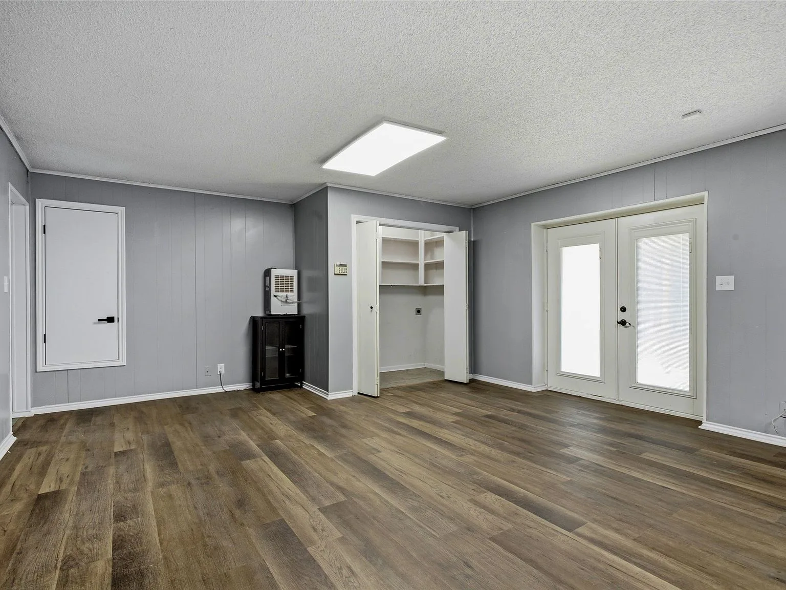 Lower level living area with light grey walls and wood-look plank flooring