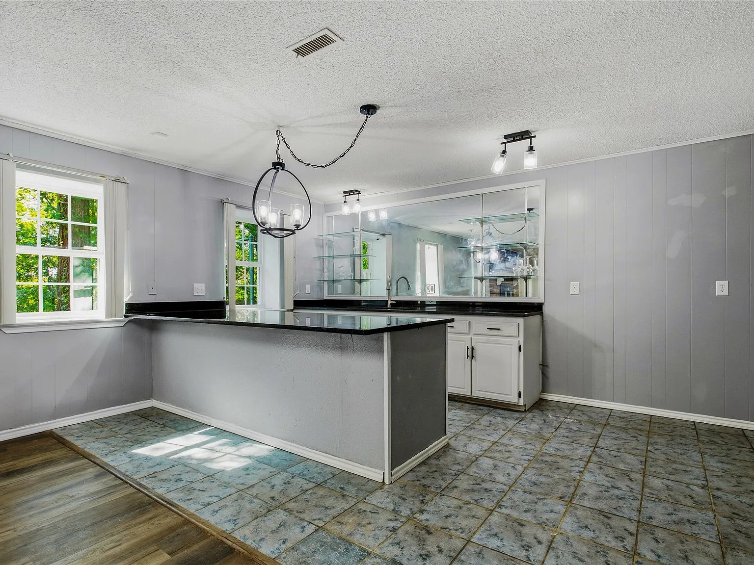 Basement kitchenette with grey walls, black granite countertops, and white cabinetry