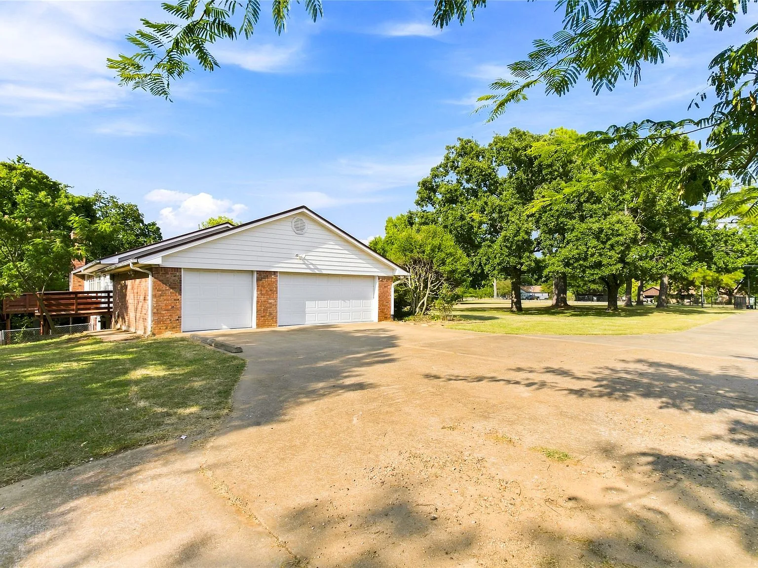 Side exterior view showing garage and driveway with bright sunny conditions