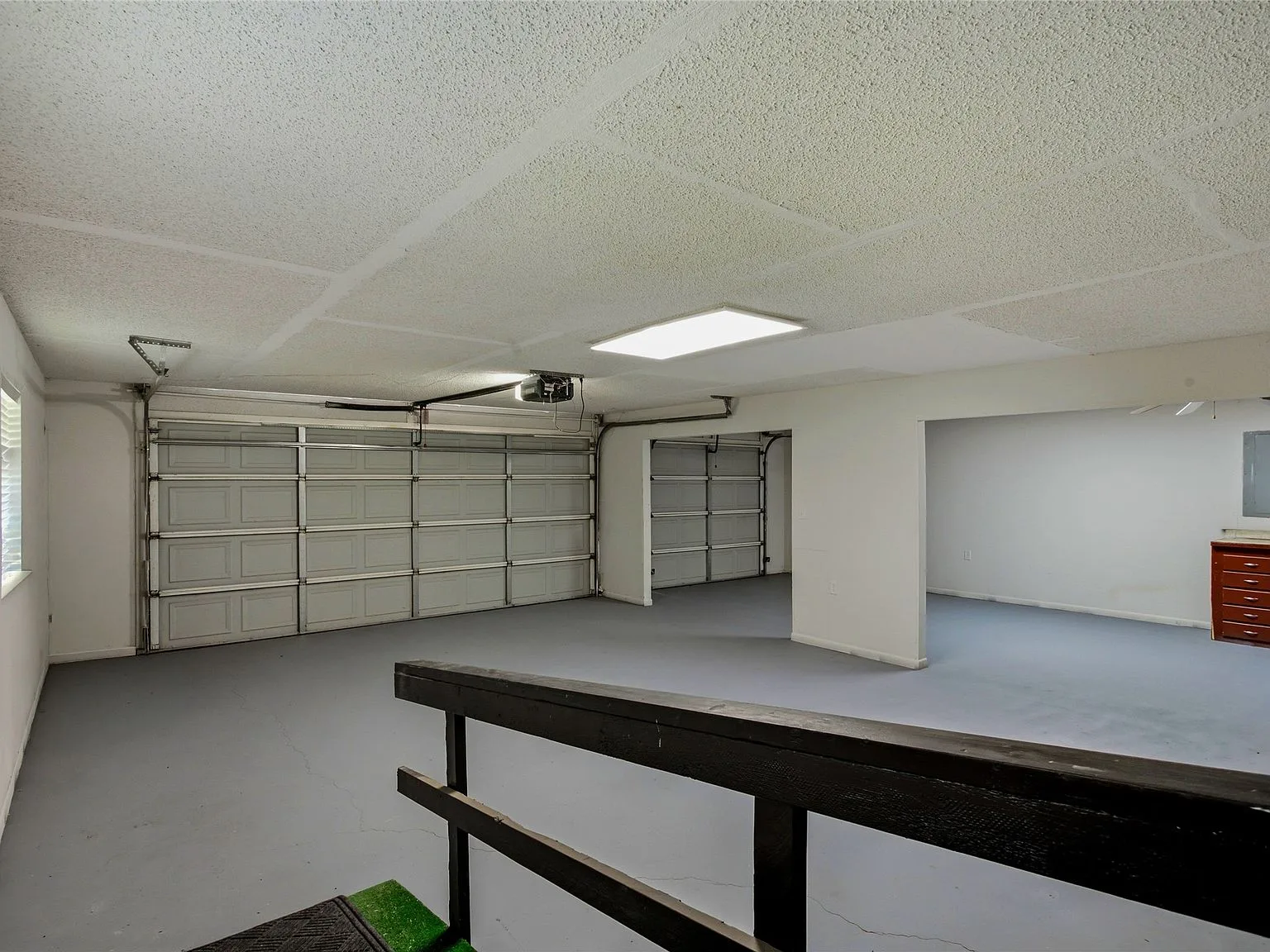 Spacious multi-car garage with concrete flooring and white sectional doors