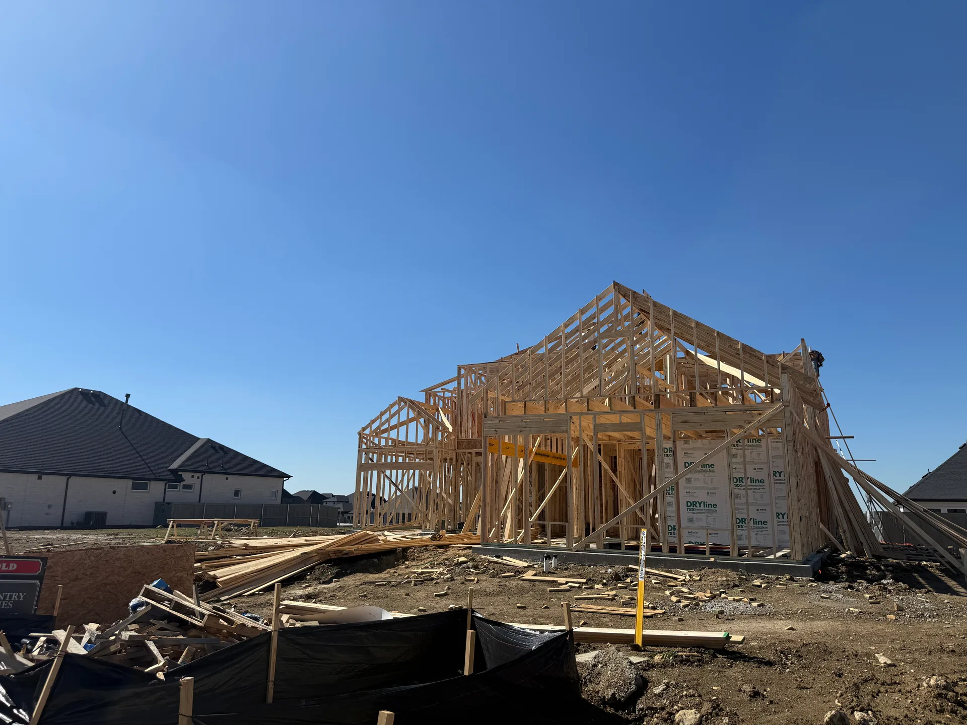 New home under construction with exposed framing and roof trusses, a Coventry Homes build at Pecan Square in Northlake, Texas