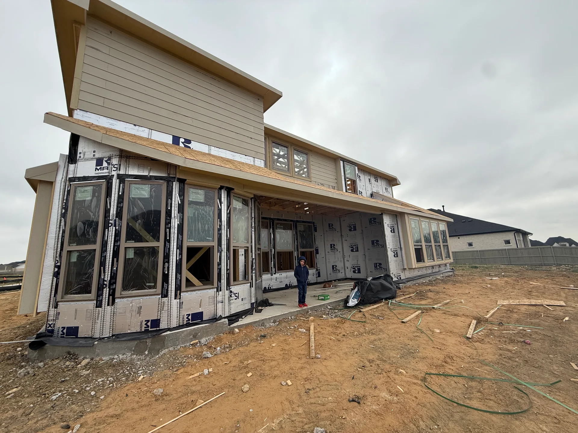 New home under construction with siding and window installation in progress, a Coventry Homes build at Pecan Square in Northlake, Texas