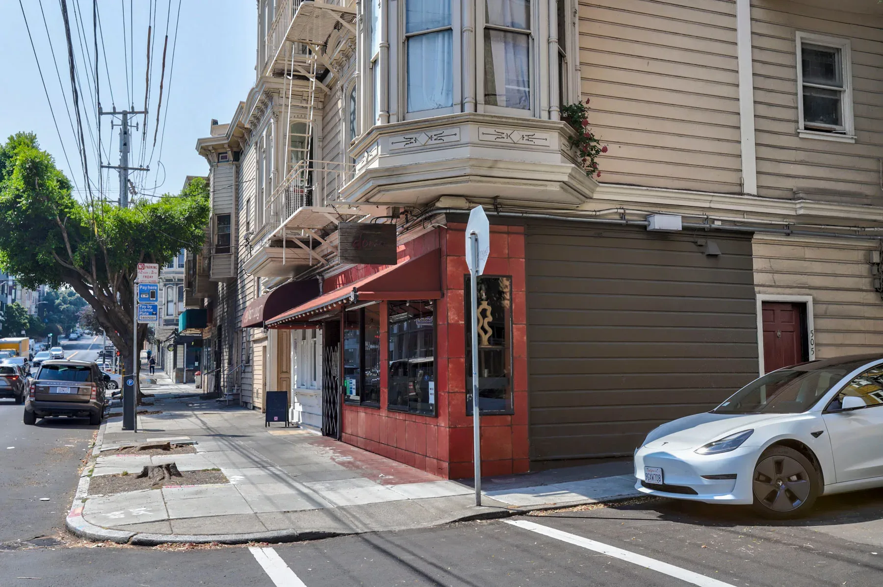 Street-level corner view of Victorian-era mixed-use building with fire escapes