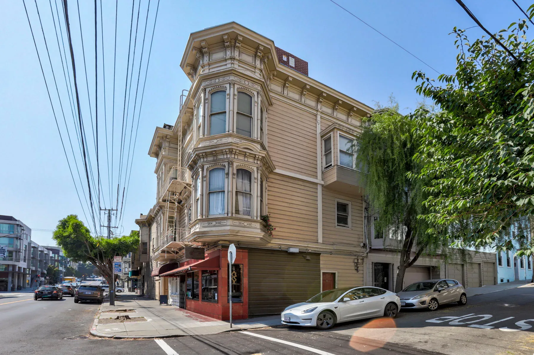 Three-story historic corner building with Victorian bay windows and red storefront