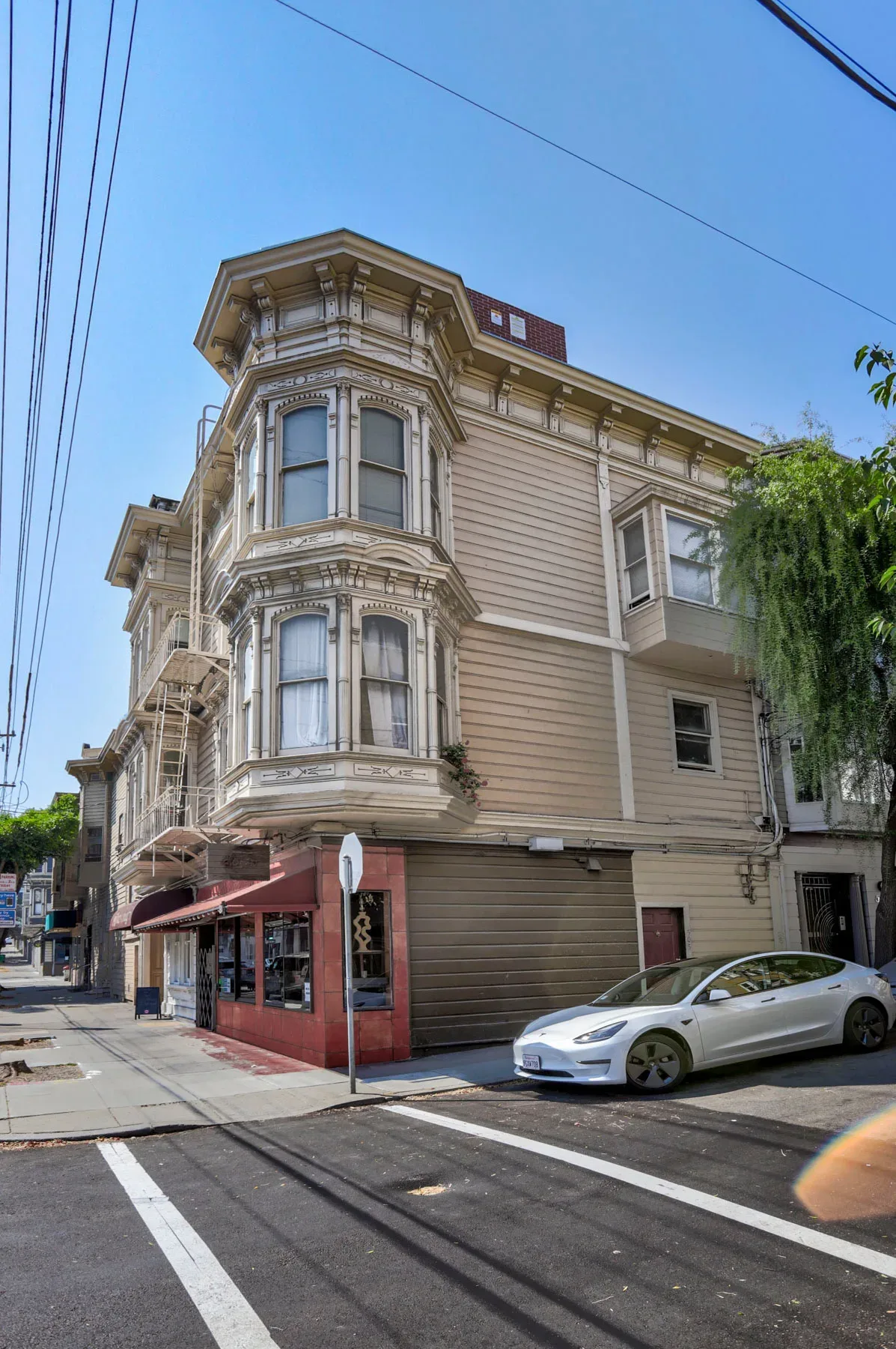 Corner perspective of three-story building with Victorian bay windows and clapboard siding