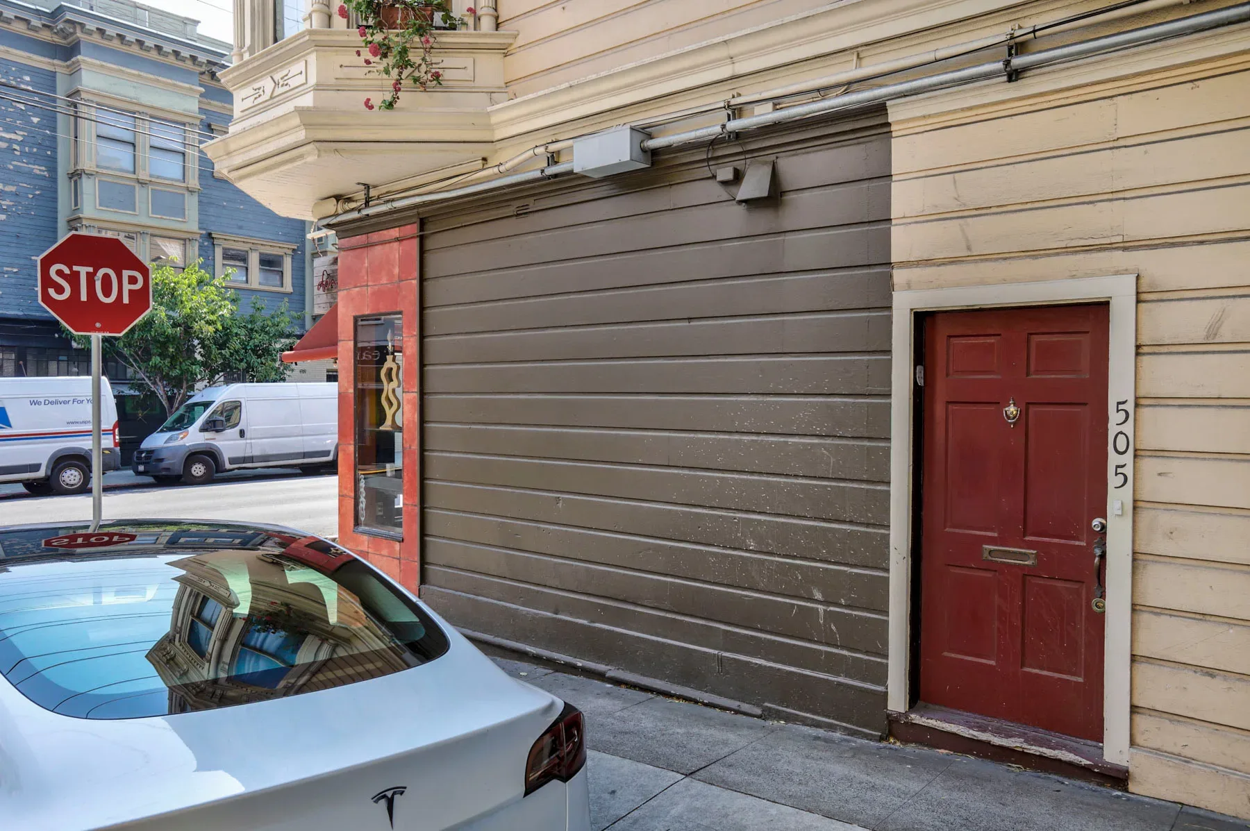 Street-level corner view showing red front door and historic building facade