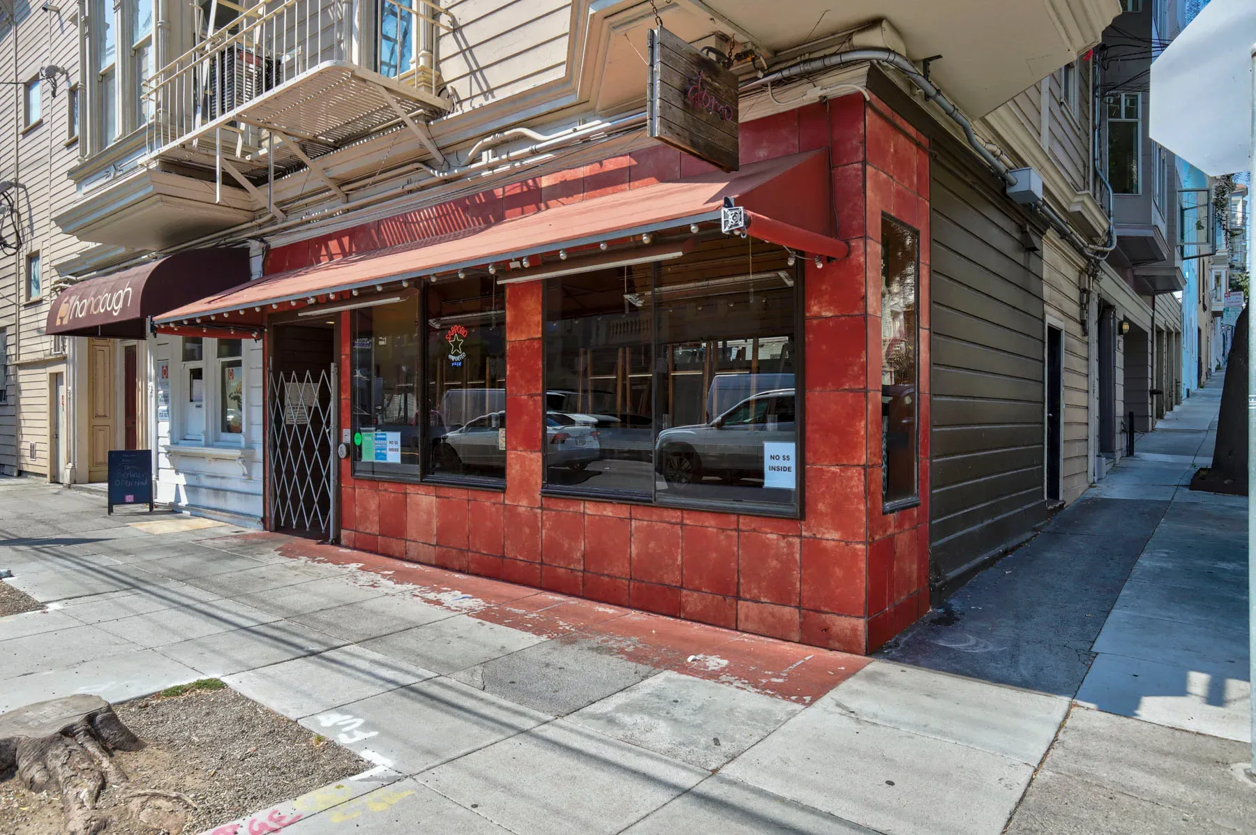 Commercial corner facade with red tiled storefront and red awning