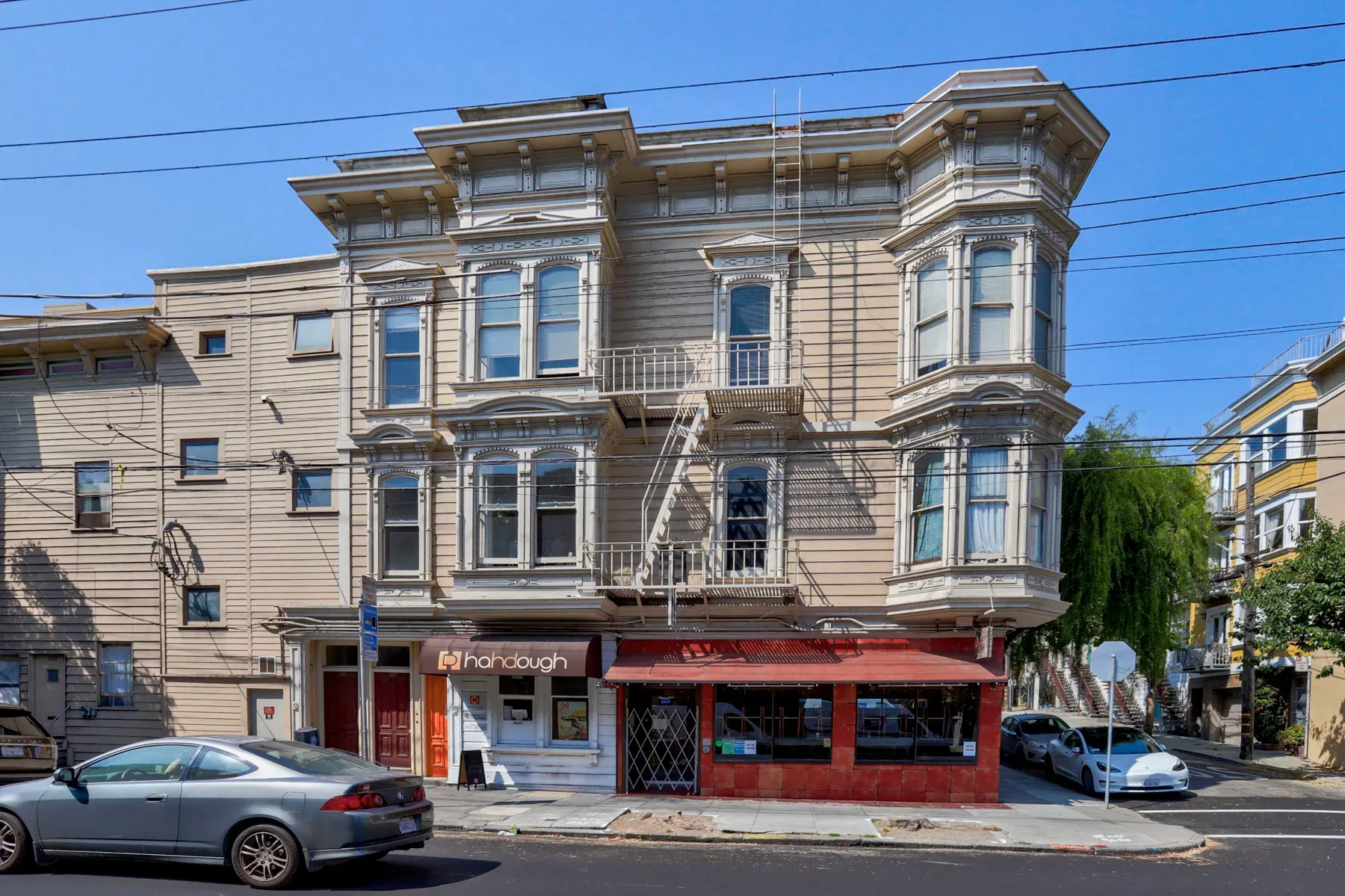 1885 Victorian facade with wood siding, bay windows, and metal fire escape