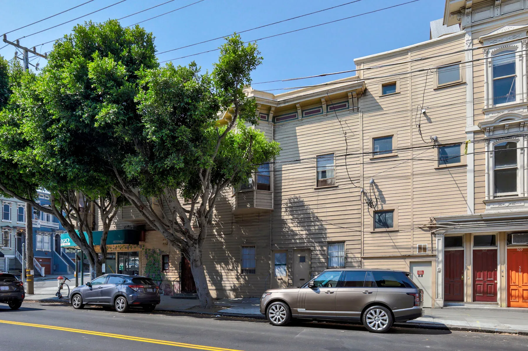Multi-story mixed-use building with beige wood siding and classic trim